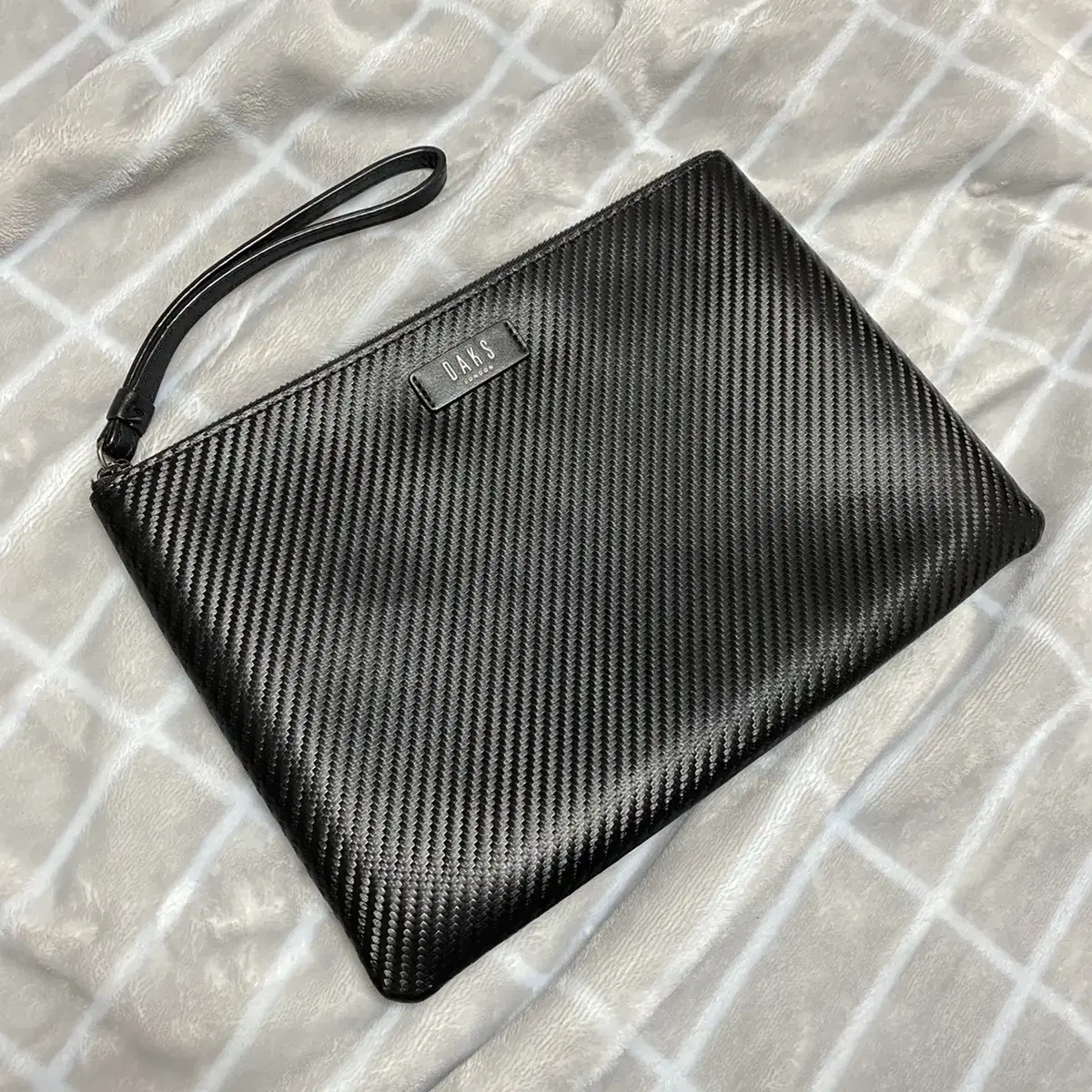 We are selling a medium-sized clutch bag made of embossed leather with a diagonal line.