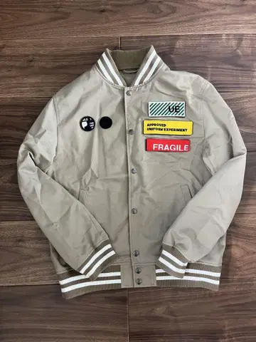 UNIFORM EXPERIMENT 베이지 바시티 자켓