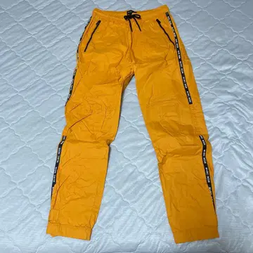 M+RC NOIR(마르쉐노아) 로고 테이프 나일론 트랙 팬츠 주황