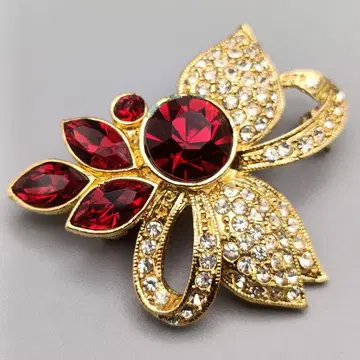 우아한 심홍의 빛깔 골드톤 브로치 리본과 꽃이 짜내는 화려한 디자인