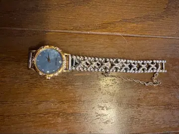 파란색 다이얼과 금속제 밴딩을 가진 NINA RICCI 시계.